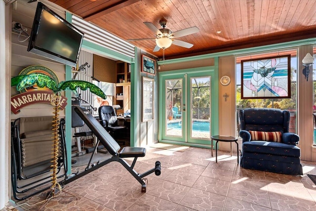 exercise room featuring wood ceiling, stone floors, and ceiling fan