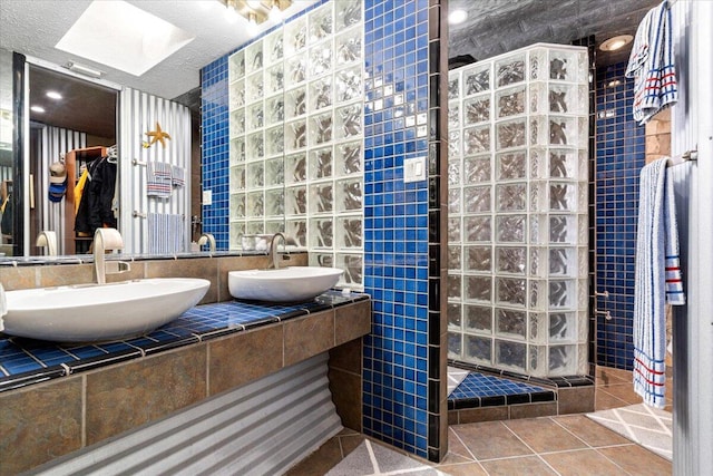 bathroom featuring tile patterned flooring, double vanity, walk in shower, and a sink