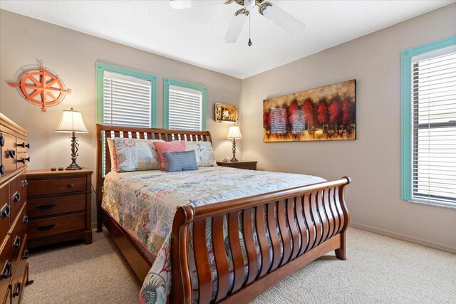 bedroom with ceiling fan, light colored carpet, and multiple windows