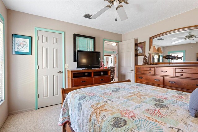 bedroom with ceiling fan, light carpet, and a textured ceiling