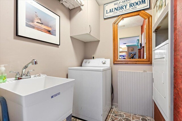 clothes washing area with sink, radiator heating unit, and cabinets