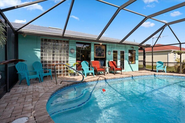 view of pool with a patio, glass enclosure, and french doors