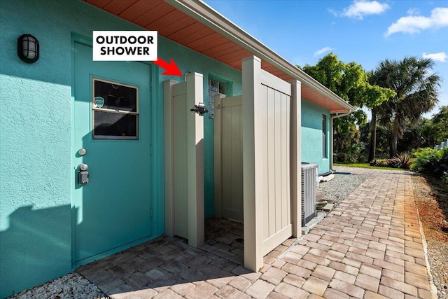 property entrance with central AC unit and stucco siding