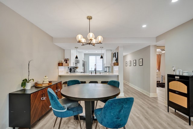 dining area featuring sink, light hardwood / wood-style floors, and a notable chandelier