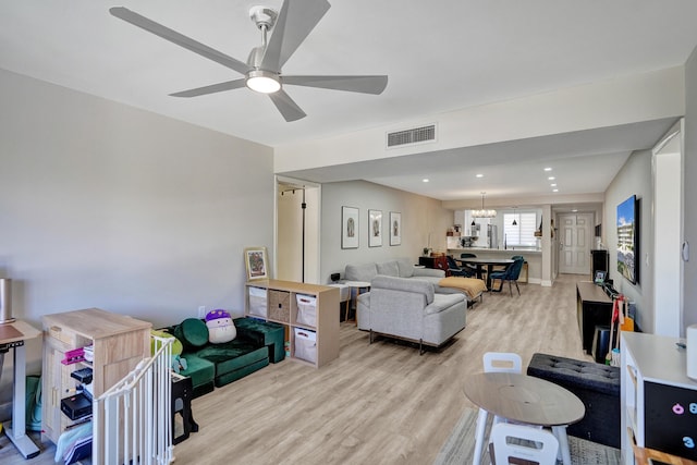 living room with ceiling fan with notable chandelier and light wood-type flooring