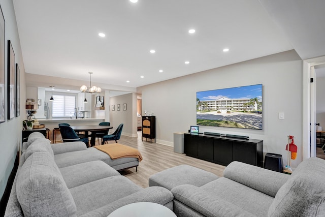 living room featuring sink, light hardwood / wood-style floors, and a chandelier