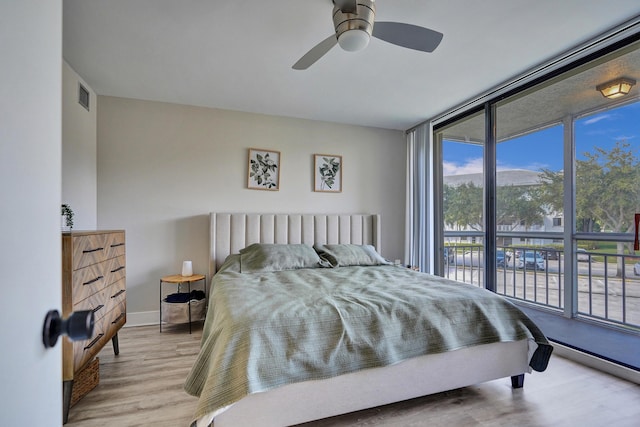 bedroom featuring light hardwood / wood-style flooring, expansive windows, and ceiling fan