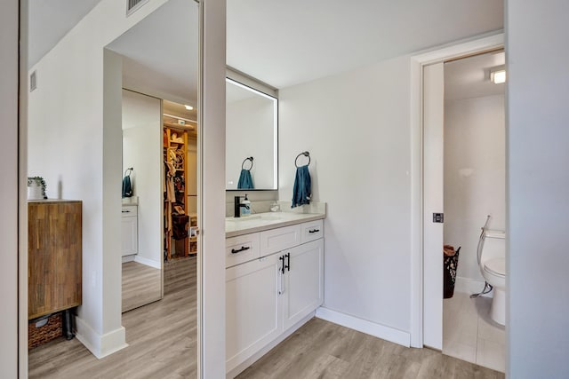 bathroom with hardwood / wood-style flooring, vanity, and toilet