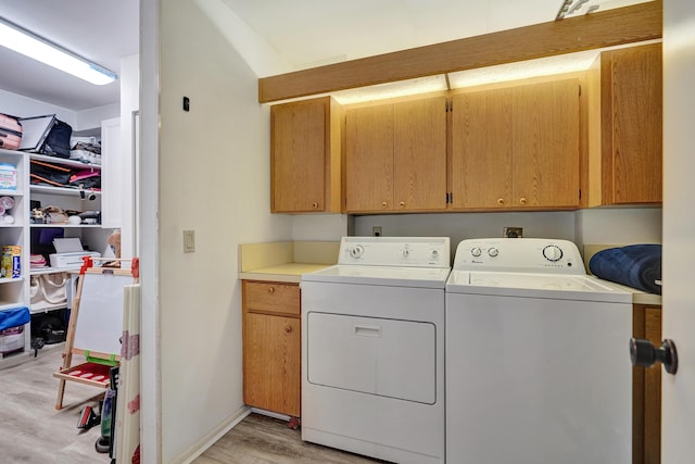 laundry area featuring independent washer and dryer, cabinets, and light wood-type flooring