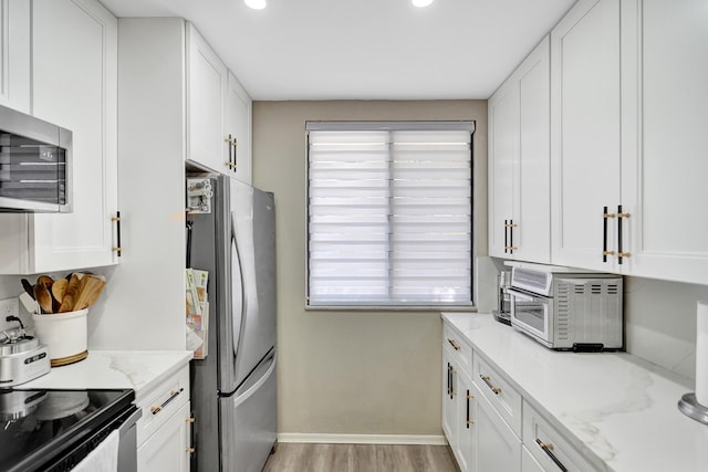 kitchen featuring light stone counters, stainless steel appliances, and white cabinets