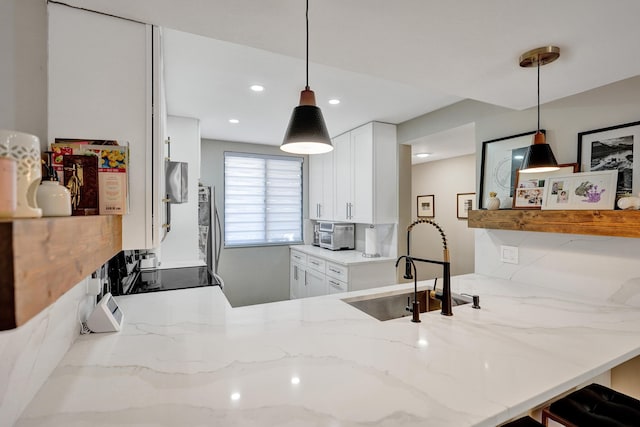 kitchen featuring white cabinetry, decorative light fixtures, sink, and light stone counters