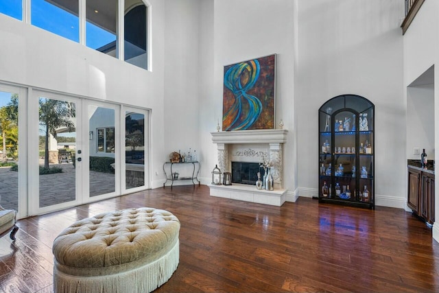 living room with a towering ceiling, dark wood-type flooring, and french doors