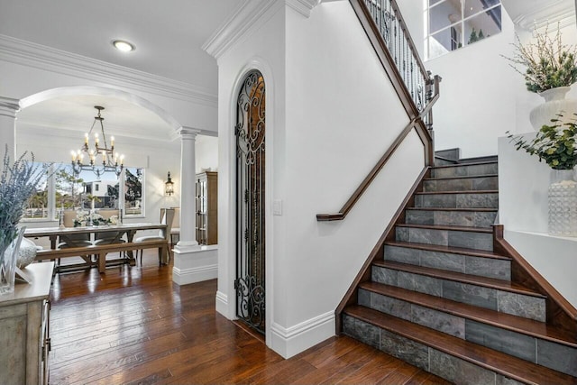 stairway with decorative columns, ornamental molding, hardwood / wood-style floors, and a chandelier