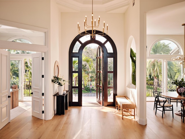 entrance foyer with a towering ceiling, light hardwood / wood-style floors, and a notable chandelier