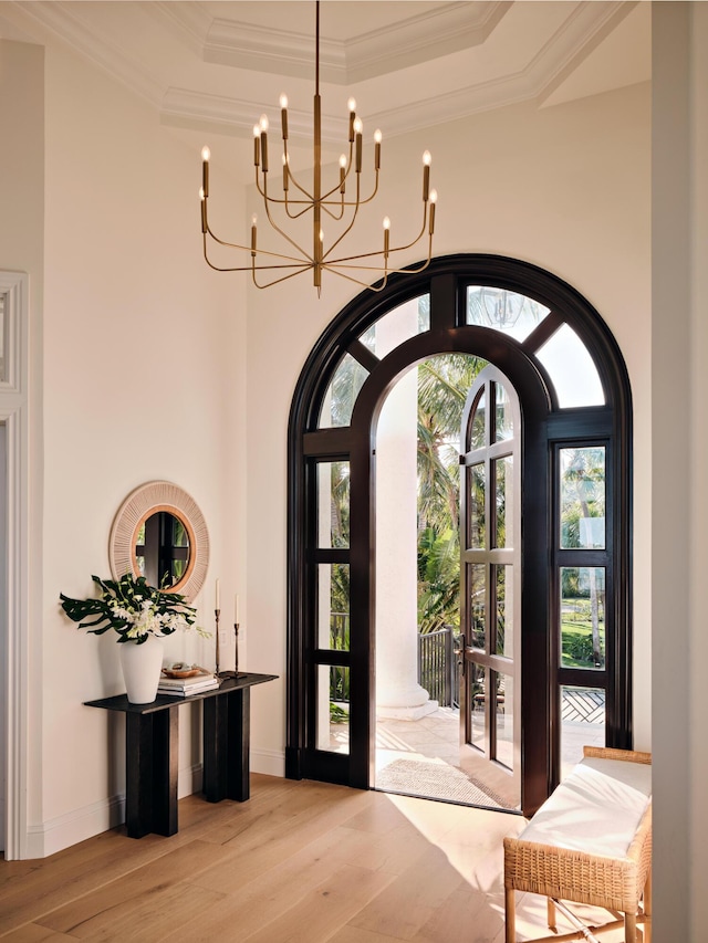 entryway with crown molding, a tray ceiling, light hardwood / wood-style flooring, and french doors