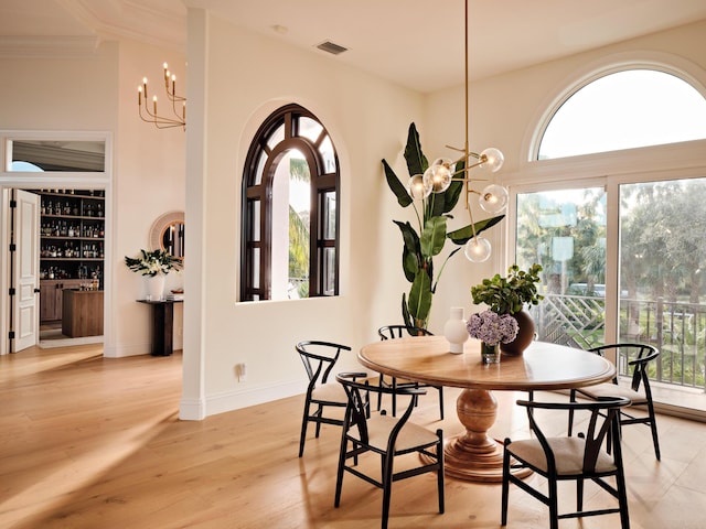 dining room featuring ornamental molding, a healthy amount of sunlight, a chandelier, and light hardwood / wood-style floors