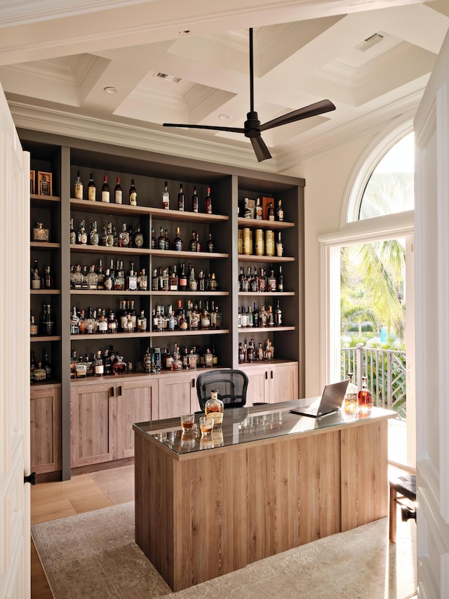 interior space featuring ornamental molding, coffered ceiling, light brown cabinetry, and ceiling fan