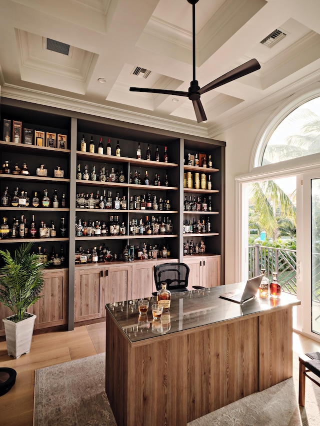 wine cellar with bar, coffered ceiling, ornamental molding, and ceiling fan