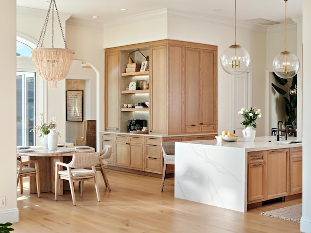 bar with a notable chandelier, hanging light fixtures, crown molding, and light hardwood / wood-style floors