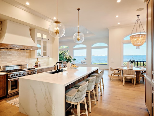 kitchen featuring pendant lighting, custom range hood, a water view, and range with two ovens