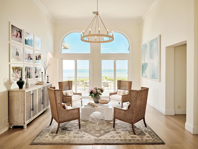 sitting room featuring ornamental molding, light hardwood / wood-style floors, a chandelier, and a water view