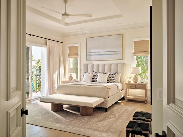bedroom with a raised ceiling, ornamental molding, access to outside, and light wood-style flooring