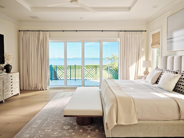 bedroom featuring crown molding, a water view, hardwood / wood-style floors, and access to exterior