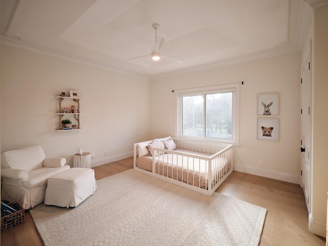 bedroom featuring a ceiling fan, crown molding, light wood-type flooring, baseboards, and a raised ceiling