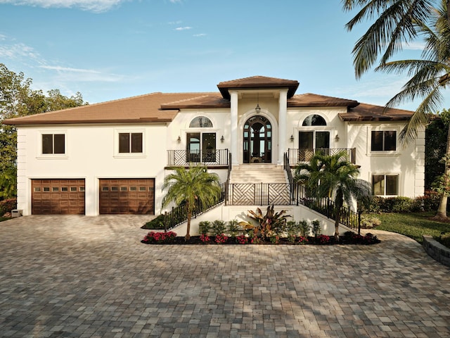 mediterranean / spanish house featuring stairs, an attached garage, french doors, driveway, and stucco siding