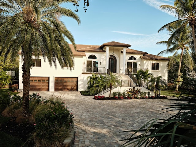 mediterranean / spanish-style house featuring driveway, stairway, stucco siding, and a garage