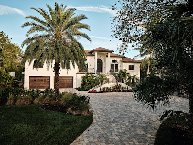 mediterranean / spanish home featuring a garage, stucco siding, and driveway