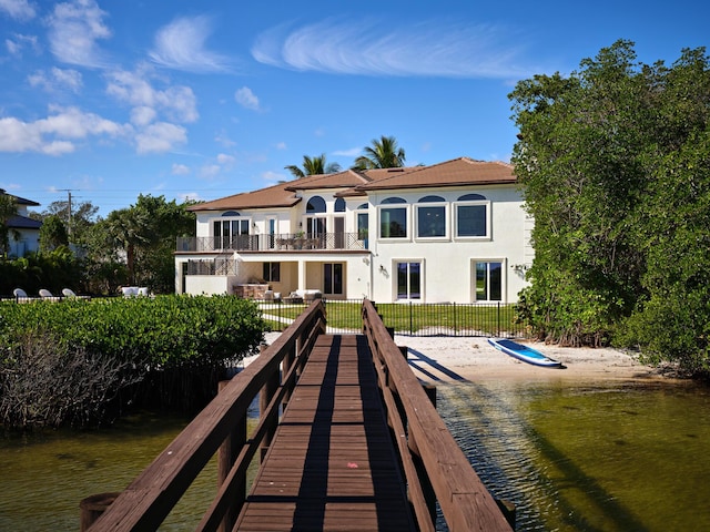 rear view of house featuring fence, stucco siding, and a balcony