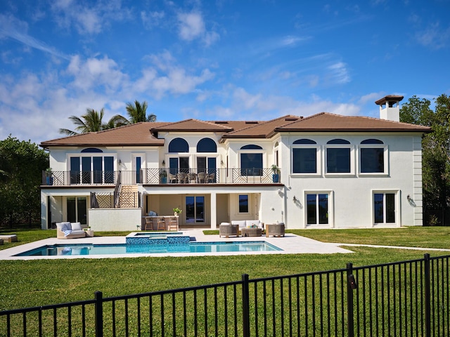 rear view of property with central air condition unit, a balcony, a lawn, an in ground hot tub, and an outdoor living space