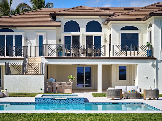 rear view of house with a balcony, an outdoor hangout area, central AC unit, a pool with hot tub, and a patio area