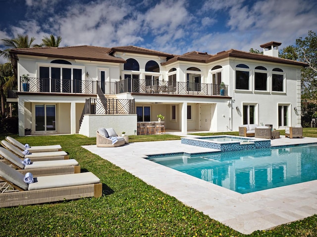 rear view of house featuring a patio, outdoor lounge area, stucco siding, a pool with connected hot tub, and a balcony