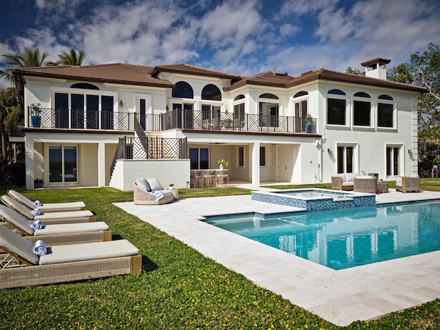 back of house with a patio area, a balcony, a yard, an outdoor bar, and a pool with hot tub