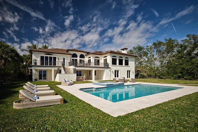 back of house featuring a balcony, a yard, a pool with hot tub, and a patio