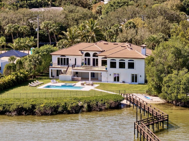 back of property with a water view, a balcony, a yard, and a patio area