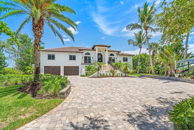 mediterranean / spanish-style house featuring stairway, stucco siding, an attached garage, and decorative driveway