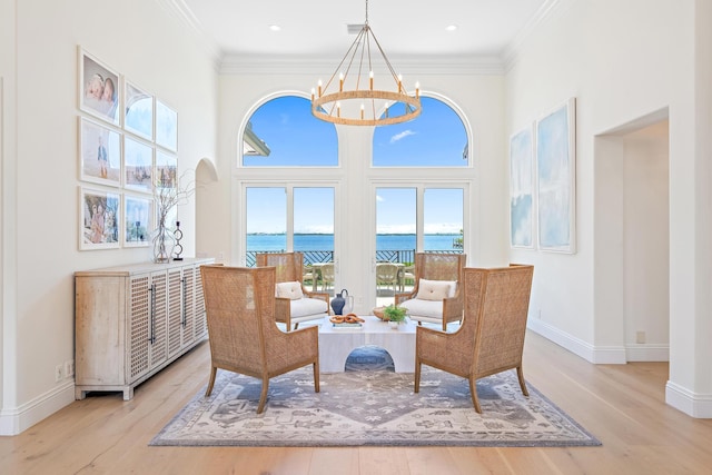 sitting room with a water view, an inviting chandelier, crown molding, and light hardwood / wood-style floors