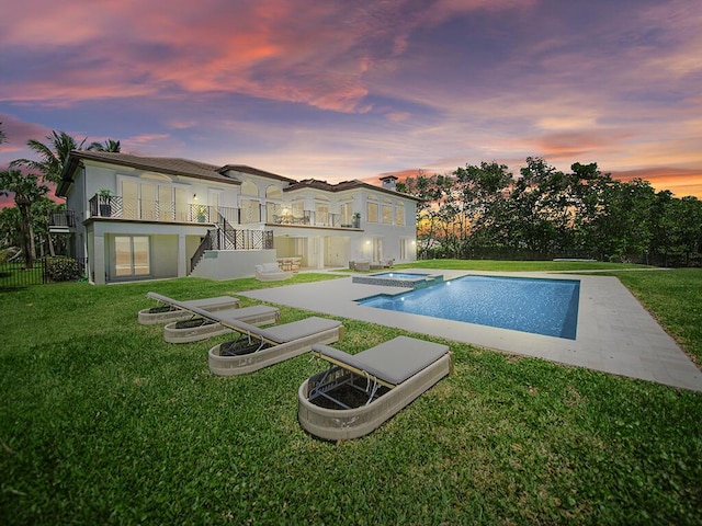 pool at dusk featuring a patio area, a lawn, and stairs