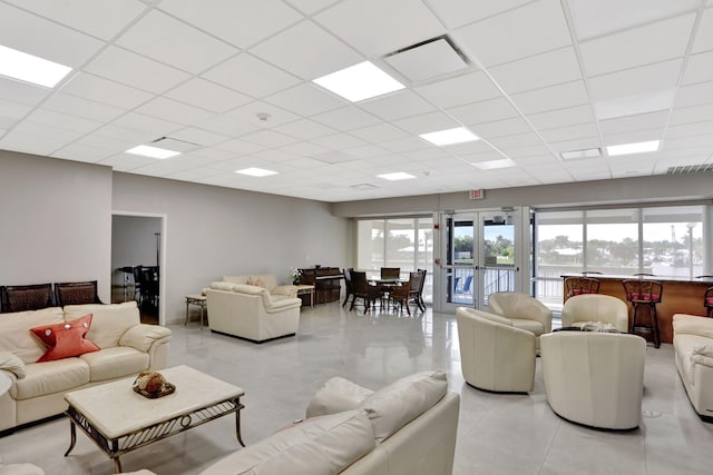 living room with light tile patterned floors and a paneled ceiling