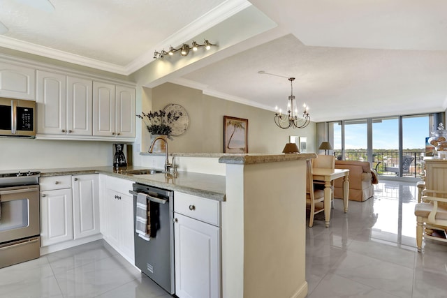 kitchen with appliances with stainless steel finishes, sink, white cabinets, hanging light fixtures, and kitchen peninsula