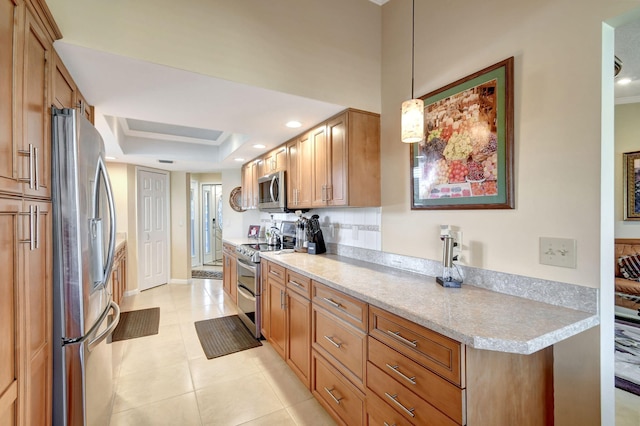 kitchen with a tray ceiling, light tile patterned floors, hanging light fixtures, appliances with stainless steel finishes, and brown cabinetry