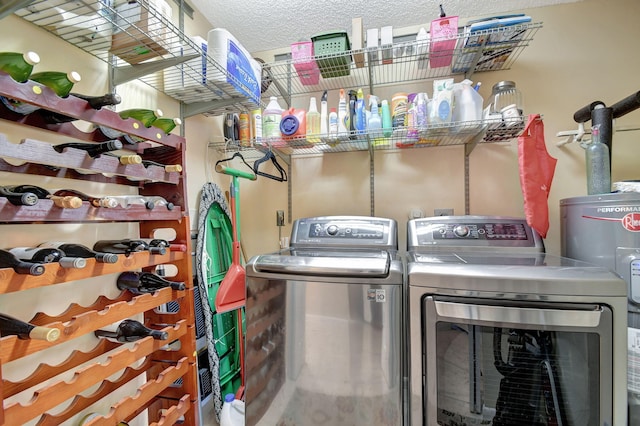 washroom featuring laundry area, water heater, a textured ceiling, and independent washer and dryer