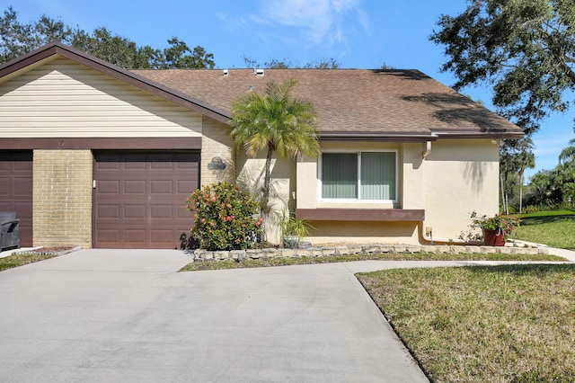 ranch-style home with driveway, stucco siding, roof with shingles, an attached garage, and brick siding