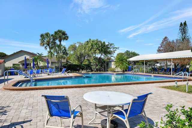 community pool with a patio area and fence