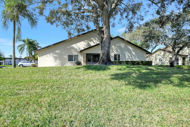 back of property featuring a yard and stucco siding