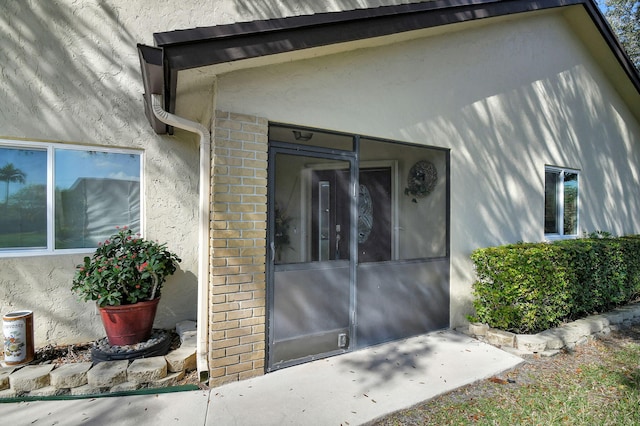 entrance to property featuring brick siding and stucco siding