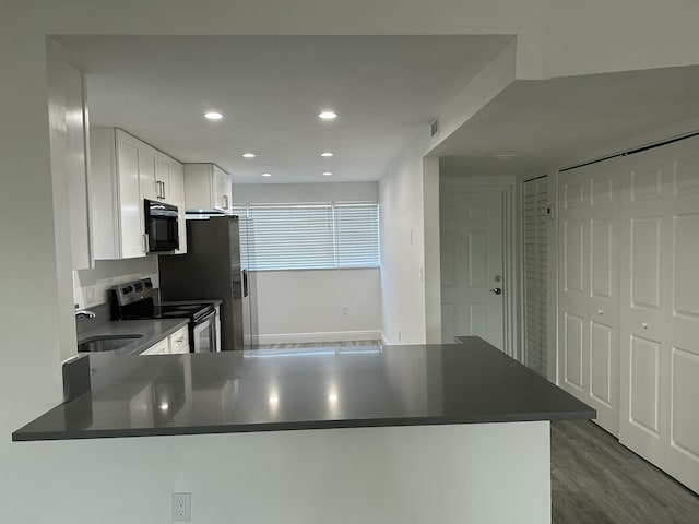 kitchen with appliances with stainless steel finishes, sink, white cabinets, and kitchen peninsula